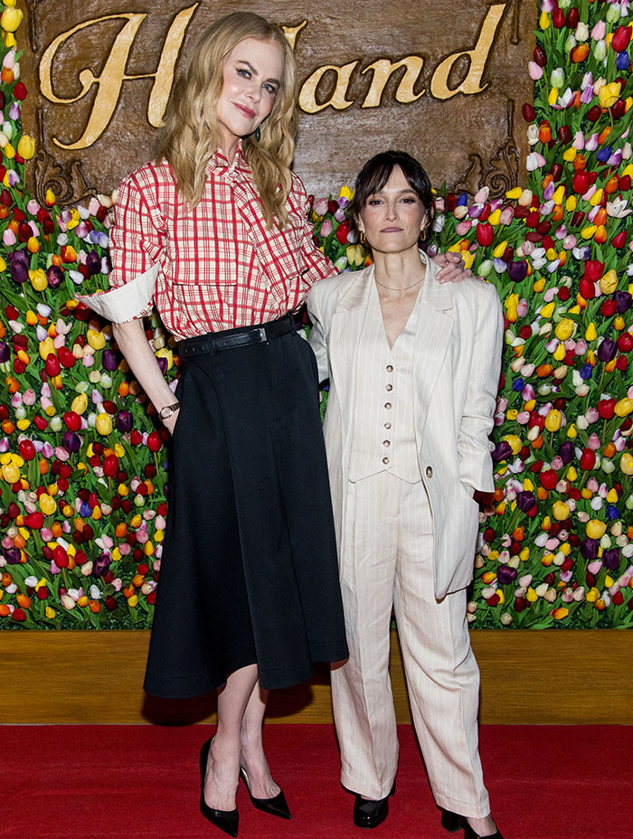 Two stars standing together at an event, showcasing super tall celebrity height differences with floral background.