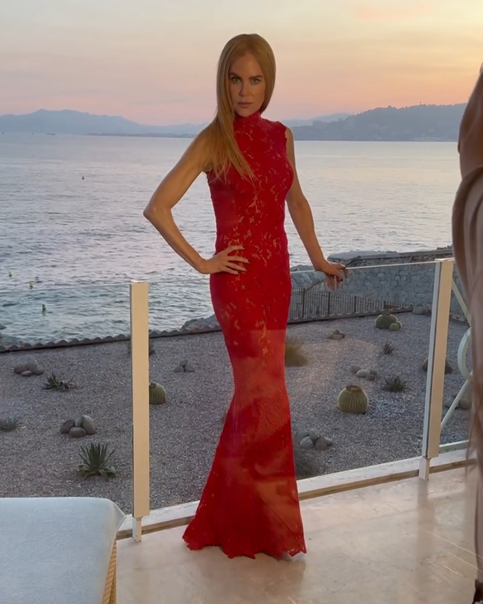 Nicole Kidman wearing a red dress by the sea, embracing her natural curls in a stunning outdoor setting.