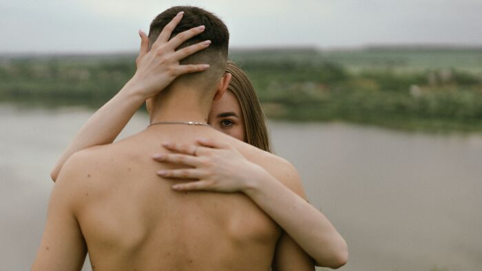 A couple embracing near a lake, illustrating romanticized behaviors that can be red flag warning signs in relationships. - 29