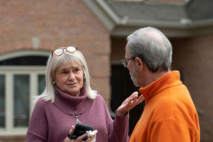 Older woman discussing driveway ownership with a man outside a house, illustrating a disabled woman driveway dispute.