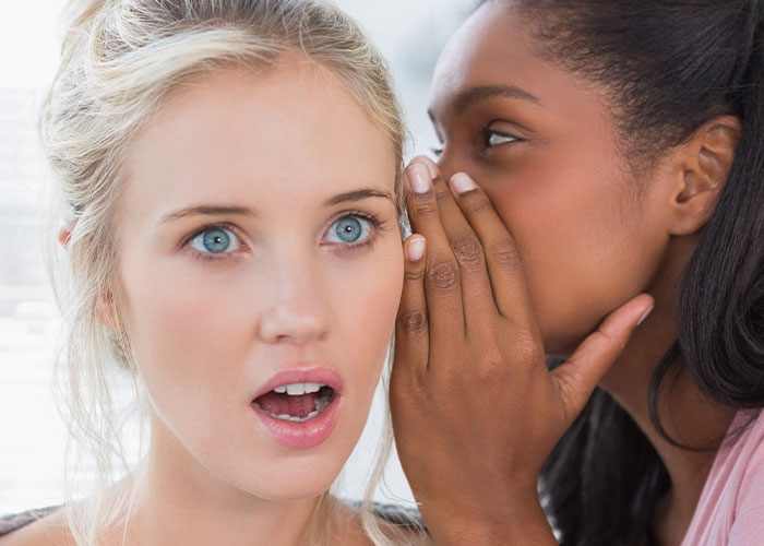 Two women whispering with shocked expression, illustrating a conflict about a nurse and an affair accusation. Two women whispering with shocked expression, illustrating a conflict about a nurse and an affair accusation.