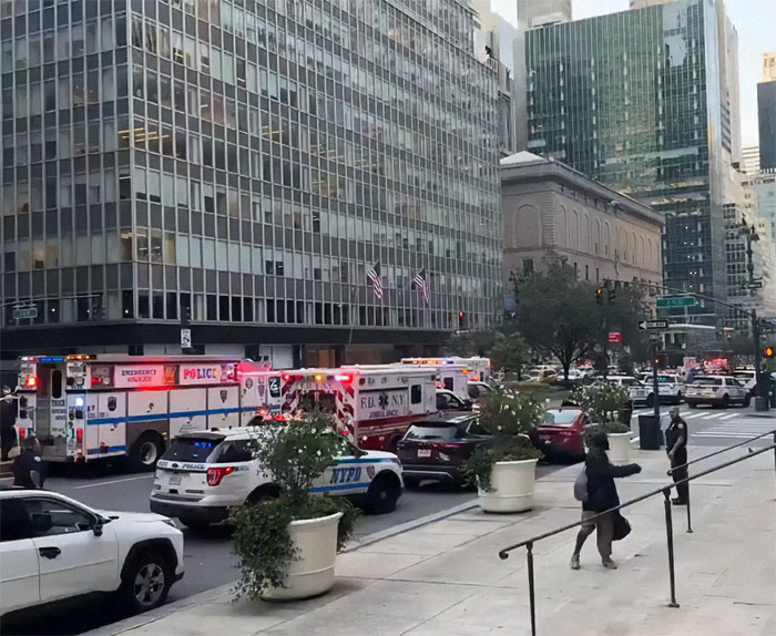 NYPD cop fatally shot while protecting others near city street with police and emergency vehicles responding.