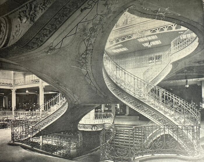 Intricate old architecture showcasing a grand spiral staircase with detailed ironwork and ornate design elements.