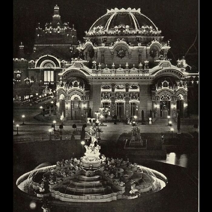 Ornate old architecture illuminated at night with detailed sculptures and a grand fountain in the foreground.