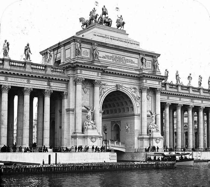 Grand old architecture with detailed sculptures and columns lining a waterfront, showcasing historic design and craftsmanship.