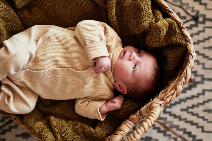 Newborn baby lying in a woven basket with cozy blankets, highlighting experiences women face after birth.