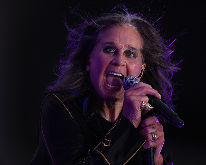 Ozzy Osbourne performing with intense expression, holding microphone on stage with dramatic lighting and flowing hair. - 1
