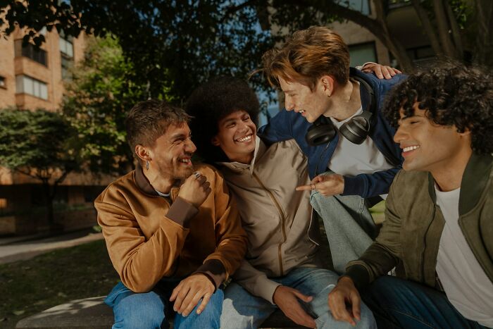 Group of men sharing laughs outdoors, illustrating things perfectly normal to men but bizarre to women.