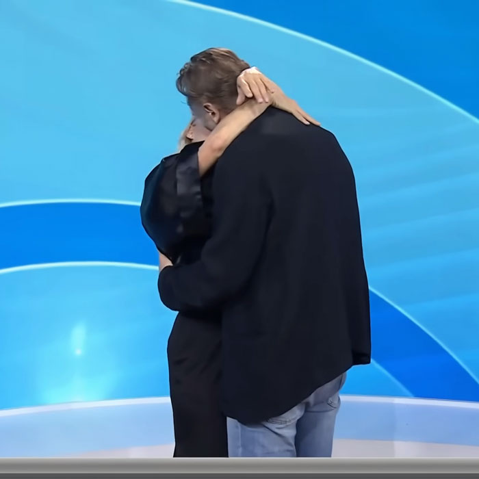 Pamela Anderson and Liam Neeson embracing on stage, showing a close moment linked to dating rumors.