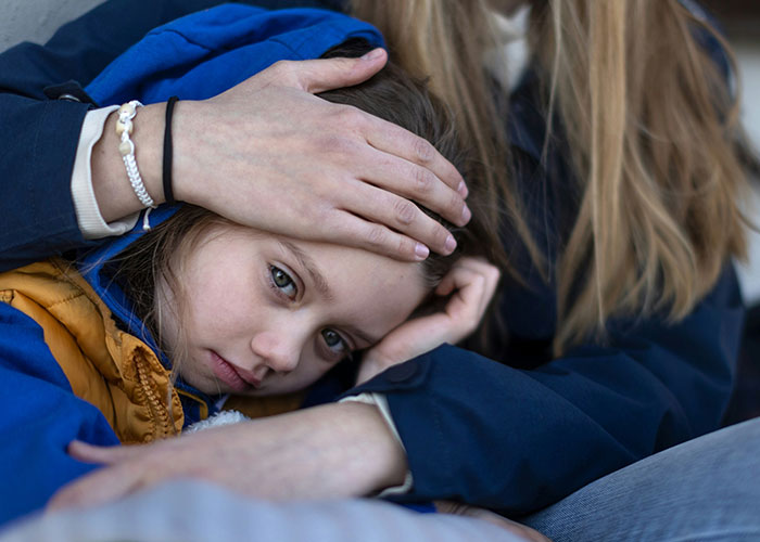 Young woman looking distressed while being comforted, illustrating struggle and feelings of being left out by parents' financial support to sister.