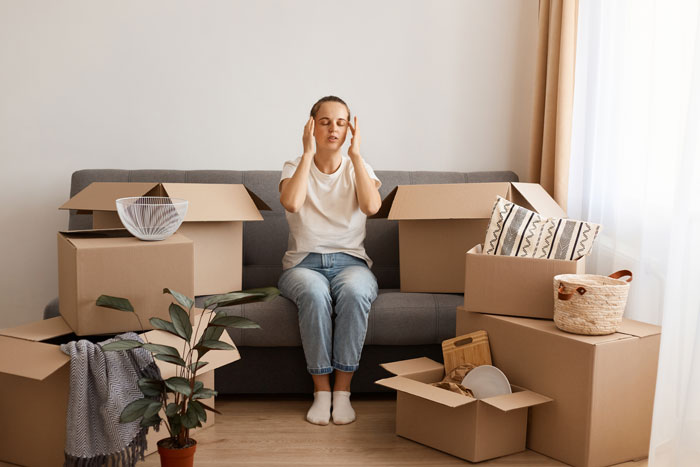 Stressed young woman surrounded by packed moving boxes, symbolizing leaving toxic parents and seeking a new home. Stressed young woman surrounded by packed moving boxes, symbolizing leaving toxic parents and seeking a new home.