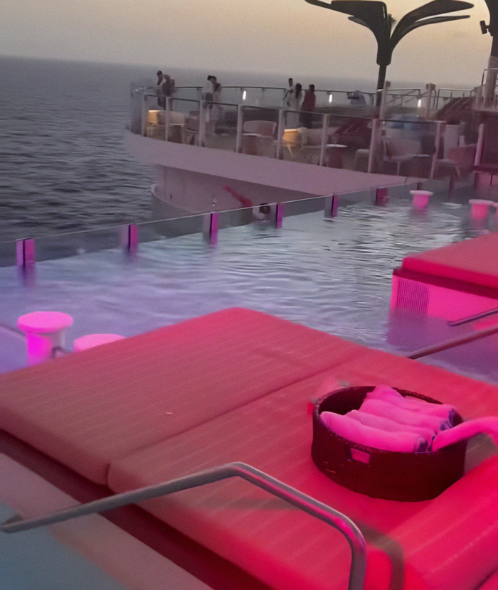 Cruise ship infinity pool at sunset with loungers and passengers near edge overlooking the ocean. - 8