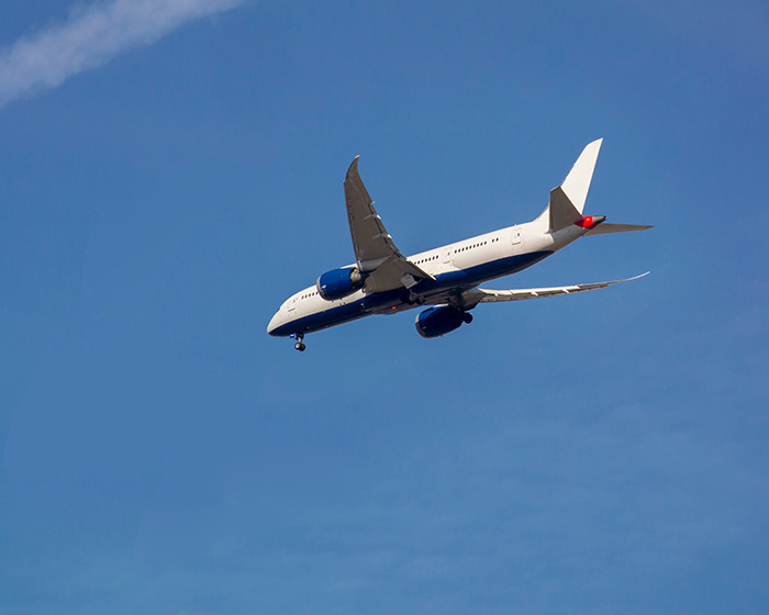 Commercial airplane flying in clear blue sky representing Japan Airlines flight experiencing sudden mid-air plunge. Commercial airplane flying in clear blue sky representing Japan Airlines flight experiencing sudden mid-air plunge.