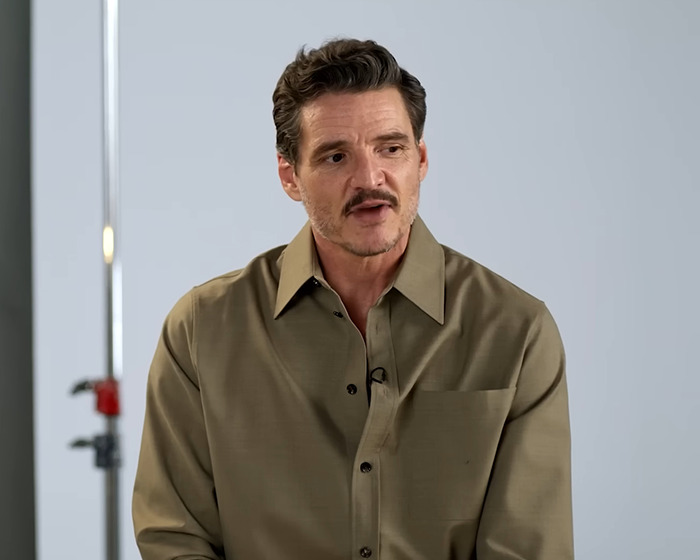 Pedro Pascal speaking during an interview, wearing a brown shirt, in a studio setting.