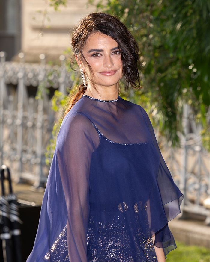 Pirates of the Caribbean actress at Paris Fashion Week wearing a sheer navy blue dress with sequins and earrings.