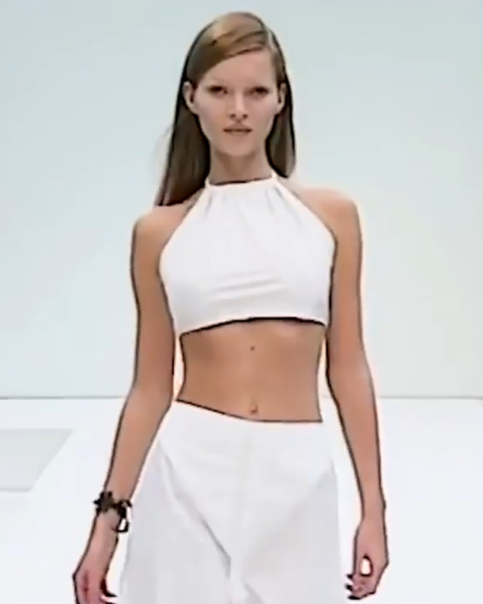 Fashion model walking on runway wearing white crop top and pants, related to Ilona Maher response to Kate Moss skinny quote. - 6