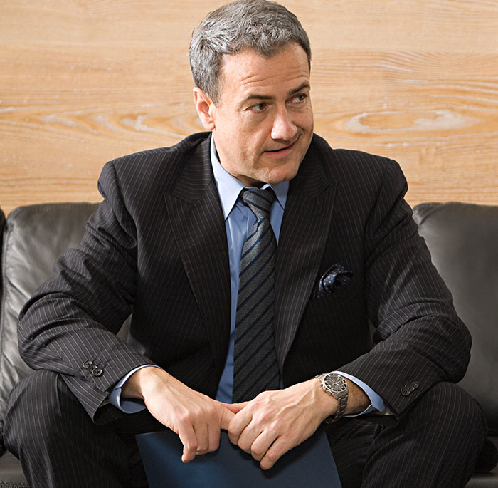 Middle-aged man in a pinstripe suit sitting on a couch, appearing confident and ready for action, depicting people had enough. - 34