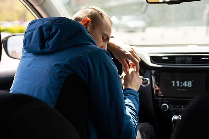 Man in a blue jacket showing frustration inside a car, illustrating moments when people had enough and took action. - 31