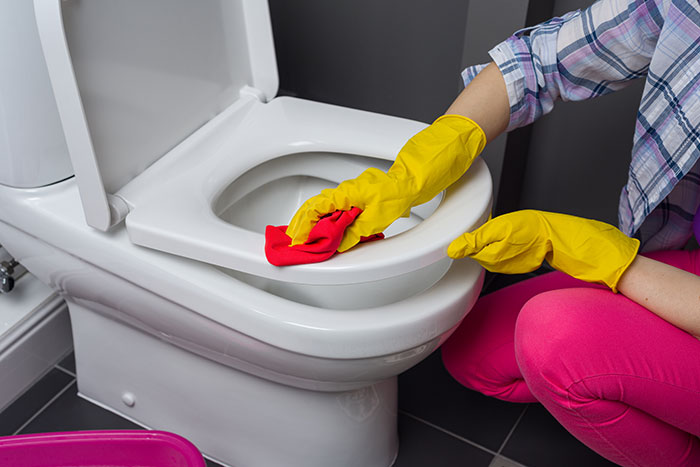 Person wearing yellow gloves cleaning a toilet seat with a red cloth showing frustration and action taken - 40