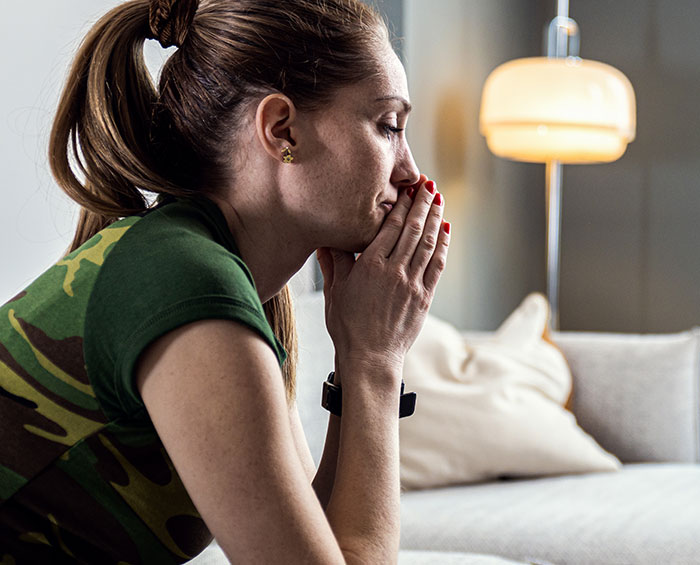 Woman in a green camo shirt sitting on a couch, looking thoughtful and determined about taking action. - 39