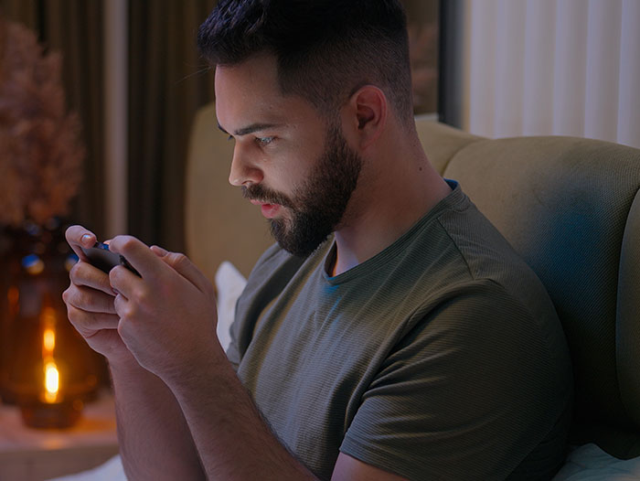 Man with beard sitting on couch, focused on smartphone, illustrating people who had enough and took action. - 43