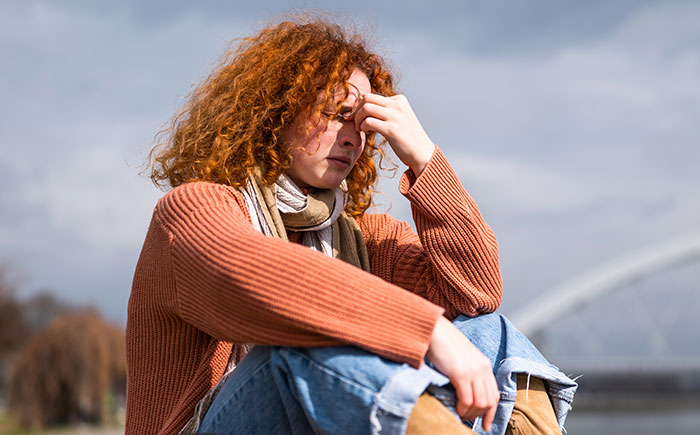 Young woman with curly red hair looking frustrated outdoors, illustrating moments people had enough and took action. - 5
