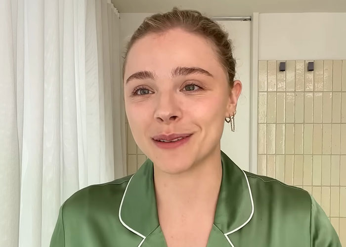 Young woman in a green satin shirt sharing experiences about people who went to school with celebrities in a casual setting.