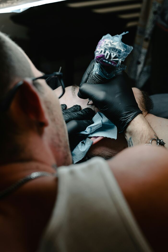 Tattoo artist wearing black gloves carefully working on a detailed tattoo, symbolizing ignored gut feeling regrets.