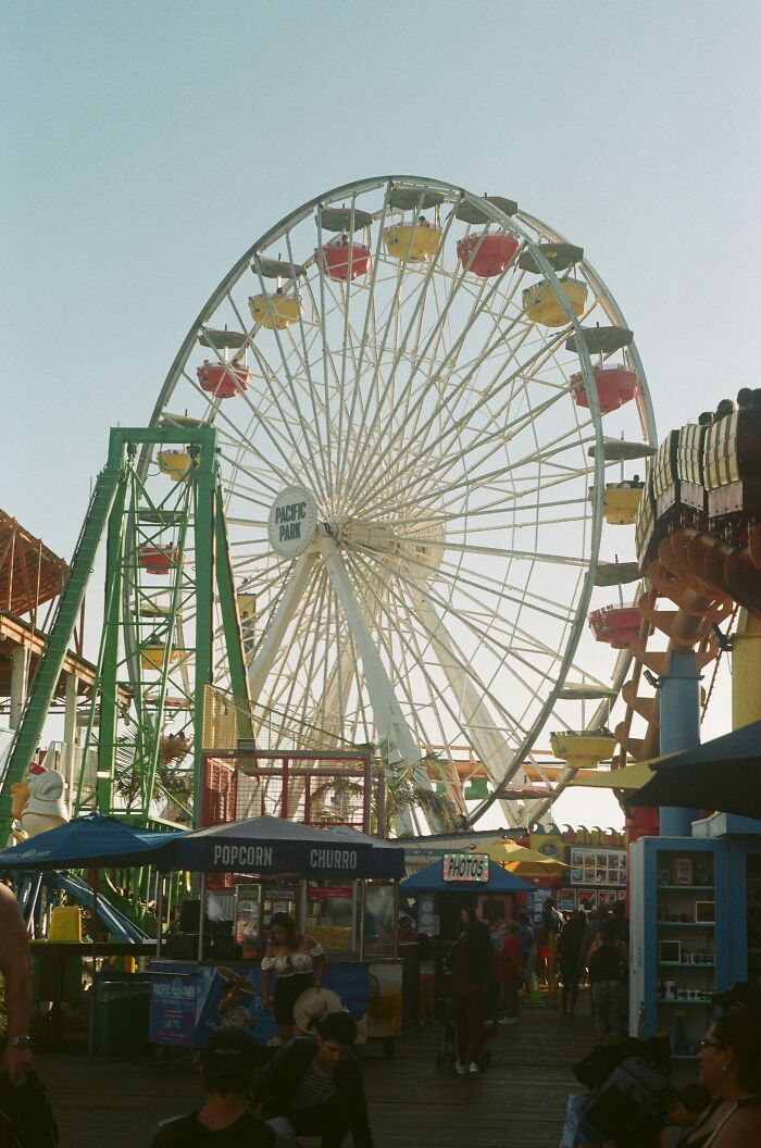 Ferris wheel at an amusement park with people and snack stands, capturing the moment that still haunts memories.