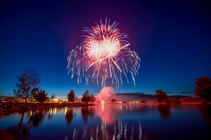 Fireworks exploding over a calm lake at night, capturing a moment that still haunts many who ignored their gut feeling.