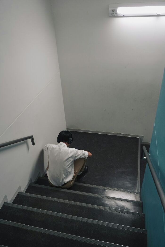 Person sitting alone on stairs wearing headphones in a dimly lit space, reflecting on relationship red flags. - 9