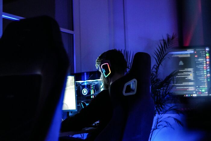 Person wearing gaming headphones focused on computer screens, highlighting relationship red flags about needing a parent not a partner. - 13