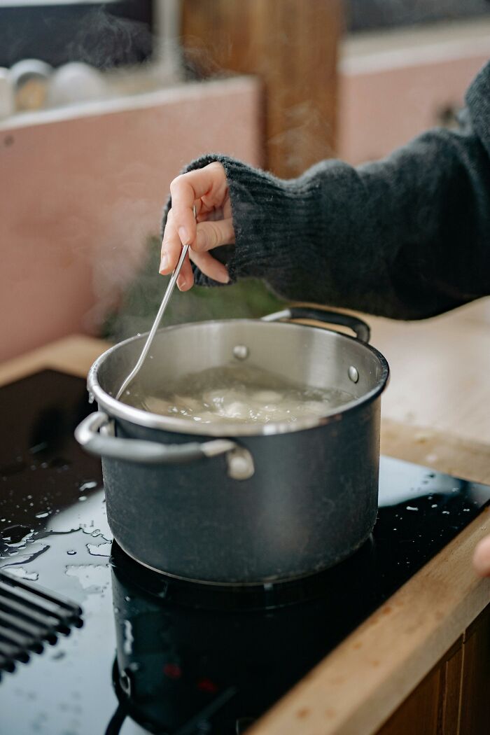 Hand stirring food in a steaming pot on stove, illustrating a parent-like care needed rather than a partner relationship. - 27