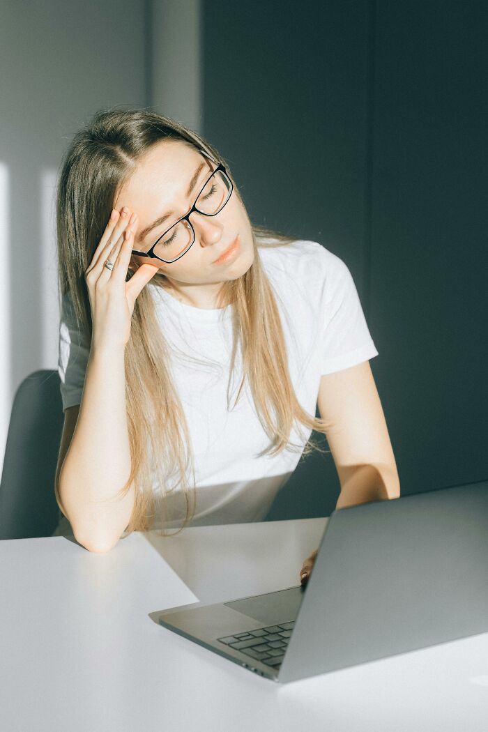 Young woman with glasses looking stressed and tired while using a laptop, reflecting sad brutal truths about life. - 5