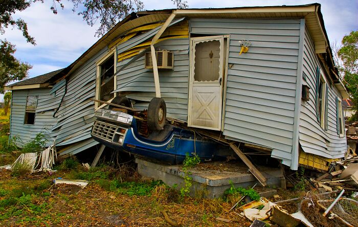 Damaged house with a car crushed underneath, illustrating a psychology experiment about perception and reality challenges.
