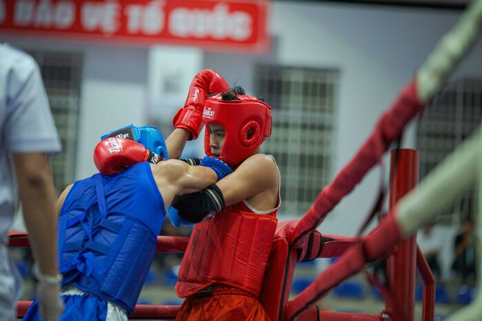 Two young athletes wearing protective gear engage in a boxing match, illustrating key psychology experiments on human behavior.
