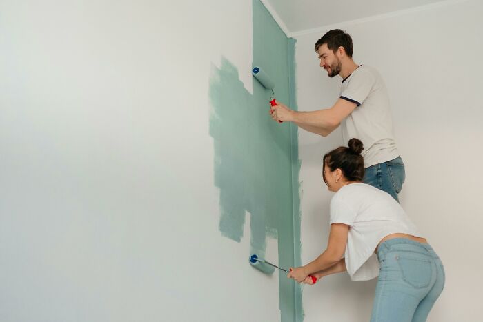 Pareja pintando una pared en casa, mostrando esfuerzo y colaboración, ilustrando secretos que las empresas ocultan.