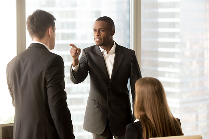Two workers confronting their boss in an office setting, capturing moments of courage calling out management.
