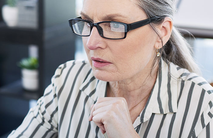 Middle-aged woman with glasses looking focused and concerned while working, representing workers calling out their bosses.