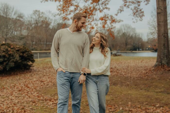 Couple walking in park during autumn, smiling and holding hands, symbolizing romanticized red flag relationship issues. - 27