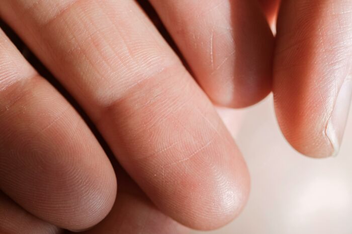 Close-up of human fingers showing detailed skin texture and fingerprint patterns, highlighting eerie discoveries by people who deal with dead bodies.