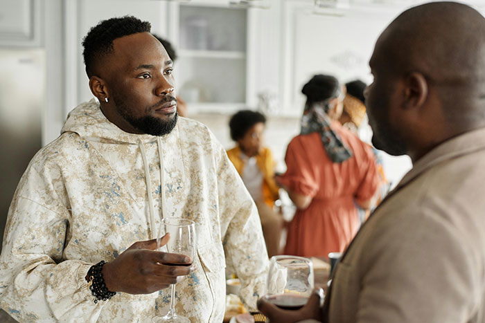 Two men in deep conversation at a family gathering, reflecting tensions around bio dad refusing babysit family drama.