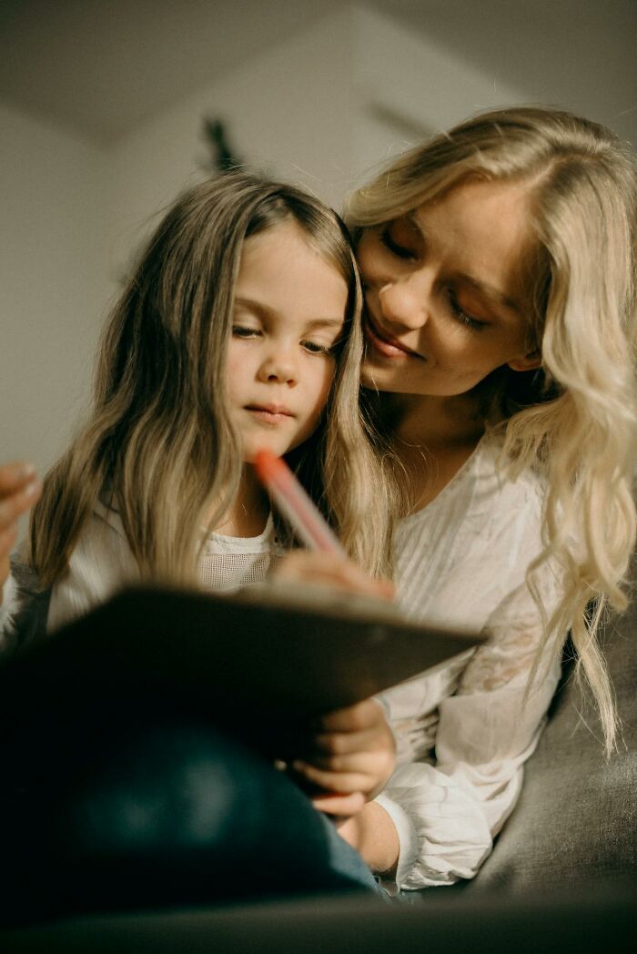 Mother and daughter sharing a moment while writing together, highlighting the importance of stay hydrated for well-being.