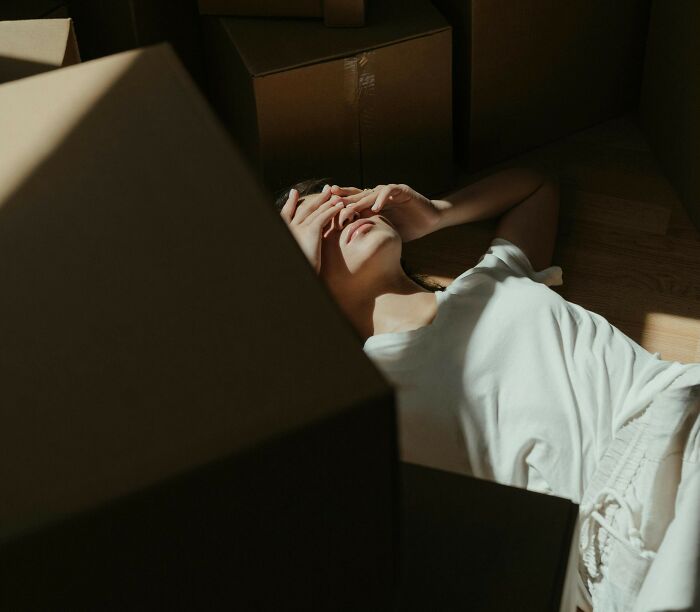 Person lying on floor surrounded by boxes, reflecting on things people share that improved life moments. - 10