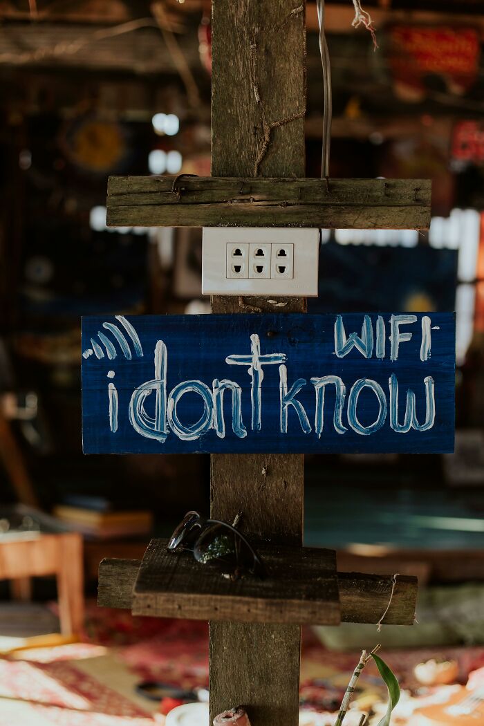 Rustic wooden sign with funny WiFi message, placed indoors with sunglasses nearby, illustrating playful pickup lines.