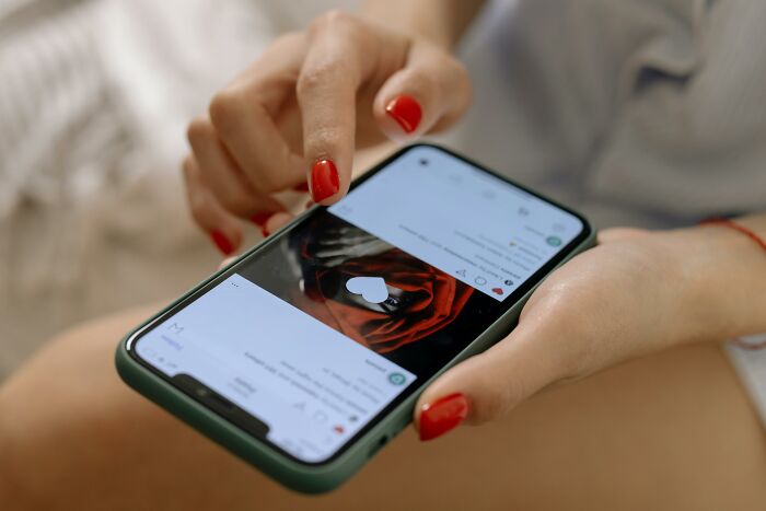 Person with red nail polish scrolling on smartphone, illustrating habits some netizens find really creepy online. - 12