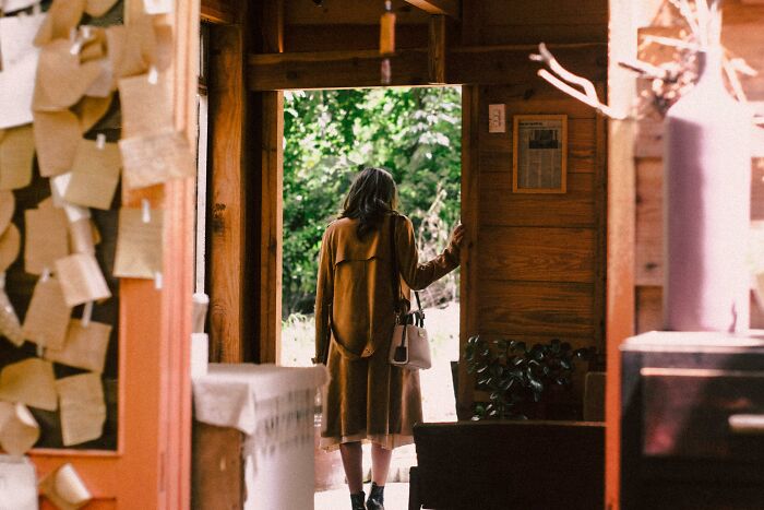 Woman entering a wooden building with natural light, illustrating how people share things that improved life experiences. - 4