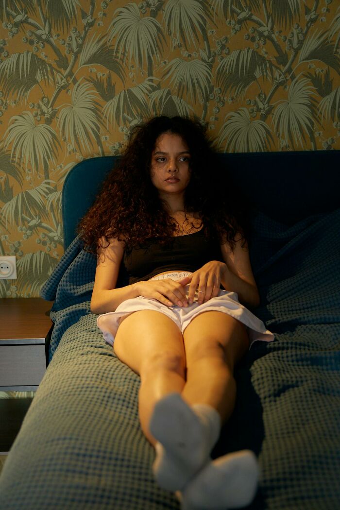 Young woman with curly hair lying on a bed, looking thoughtful and reflecting on toxic friendship experiences. - 54