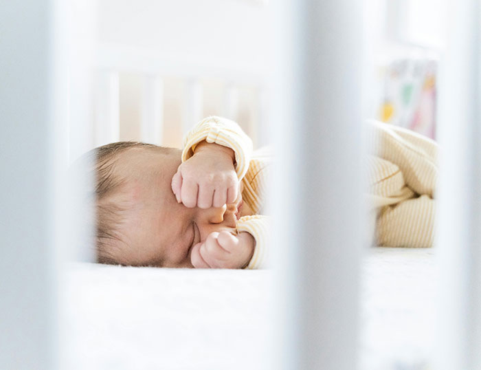 Newborn baby sleeping peacefully in crib, highlighting family drama as bio dad refuses to babysit the child.