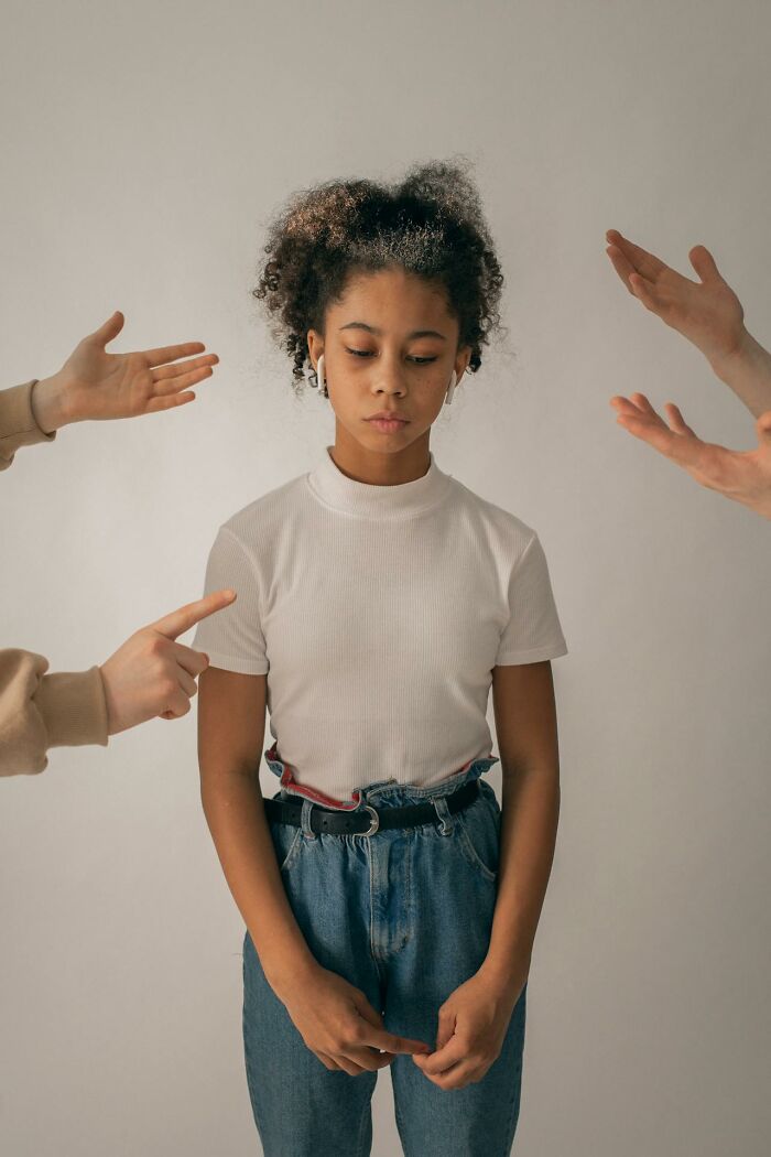 Young girl looking down sadly while multiple hands point at her representing toxic friendship and emotional struggle. - 2